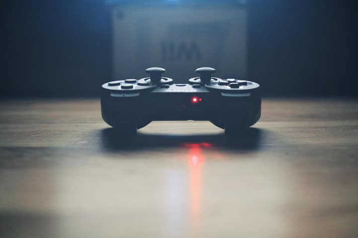 A game controller on a dark table, its light glowing red.