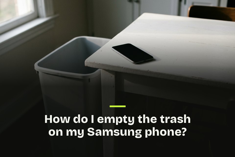 How do I empty the trash on my Samsung phone The words "How do I empty the trash on my Samsung phone?" over a picture of a phone on a white table beside an empty bin.