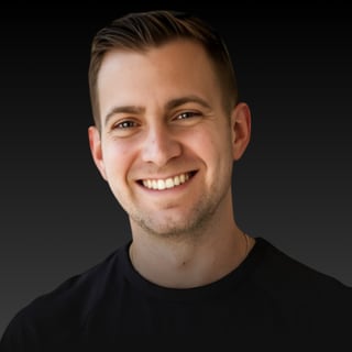 Rob Brautigam, smiling, in a black T-shirt against a dark background.