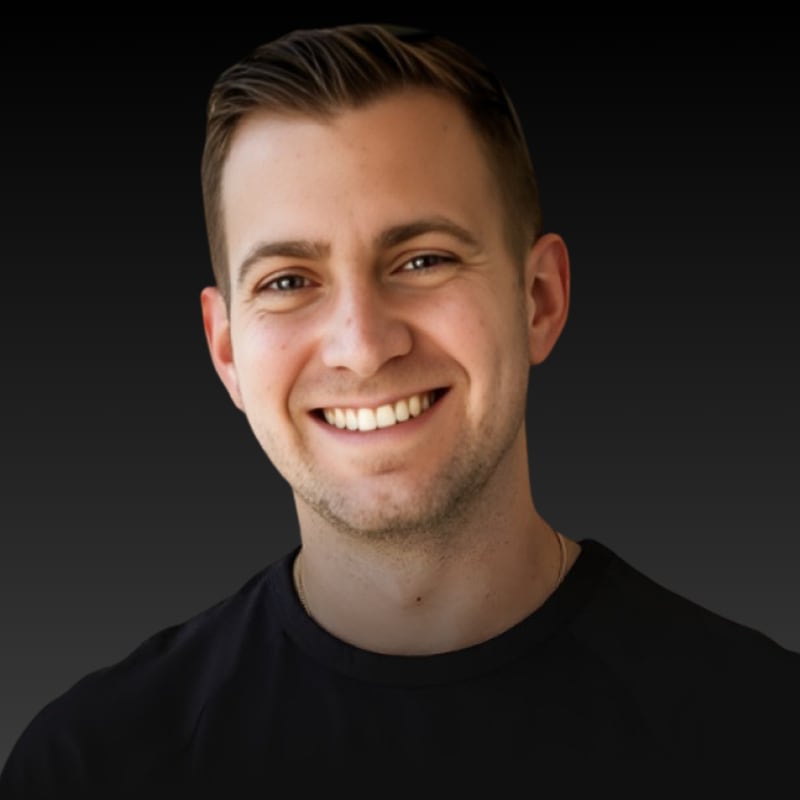 Rob Brautigam, smiling, in a black T-shirt against a dark background.