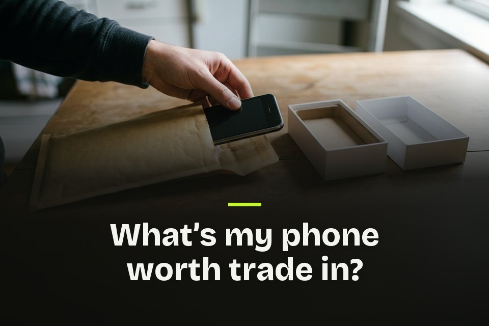 What's my phone worth trade in The words "What's my phone worth trade in?" over a hand slipping an old phone into a padded envelope by an empty box.