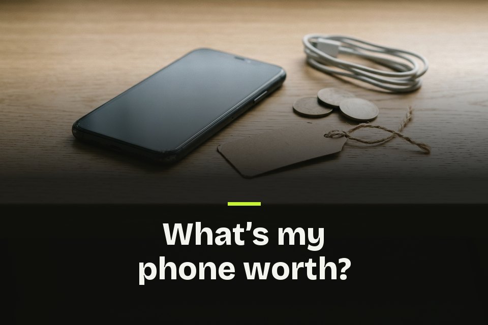 What's my phone worth The words "What's my phone worth?" over a used phone on an oak desk beside a blank price tag, coins and a cable.