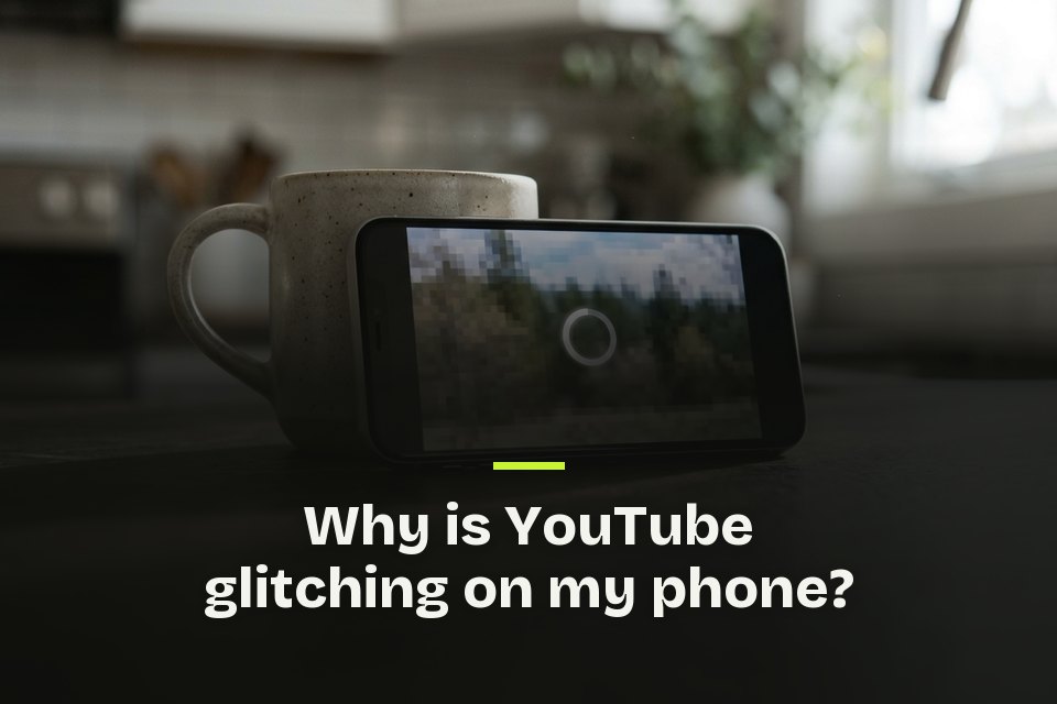 why is youtube glitching on my phone The words "Why is YouTube glitching on my phone?" over a picture of a phone propped on a mug, its video frozen and pixelated.